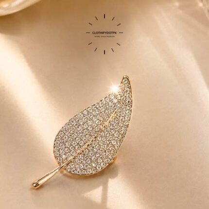 A close-up of a modern, sophisticated brooch featuring a brilliant arrangement of clear rhinestones that catch the light. By Clothifydotpk