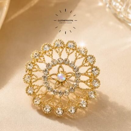A close-up of a modern, sophisticated brooch featuring a brilliant arrangement of clear rhinestones that catch the light. By Clothifydotpk