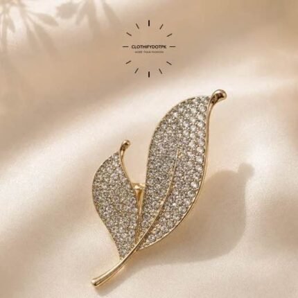 A close-up of a modern, sophisticated brooch featuring a brilliant arrangement of clear rhinestones that catch the light. By Clothifydotpk