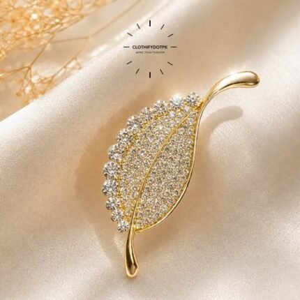 A close-up of a modern, sophisticated brooch featuring a brilliant arrangement of clear rhinestones that catch the light. By Clothifydotpk