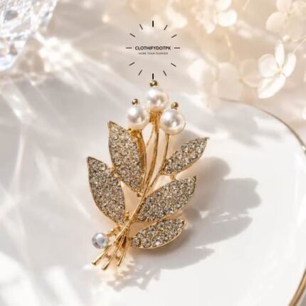 A close-up of a modern, sophisticated brooch featuring a brilliant arrangement of clear rhinestones that catch the light. By Clothifydotpk