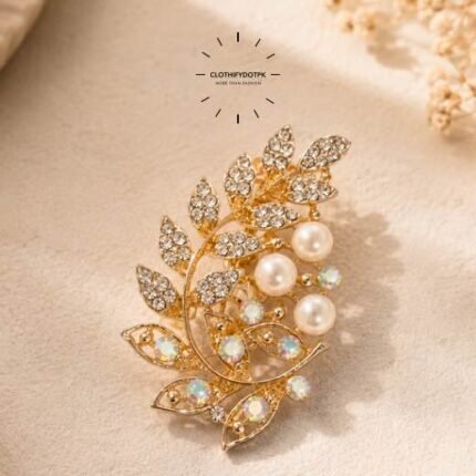 A close-up of a modern, sophisticated brooch featuring a brilliant arrangement of clear rhinestones that catch the light. By Clothifydotpk