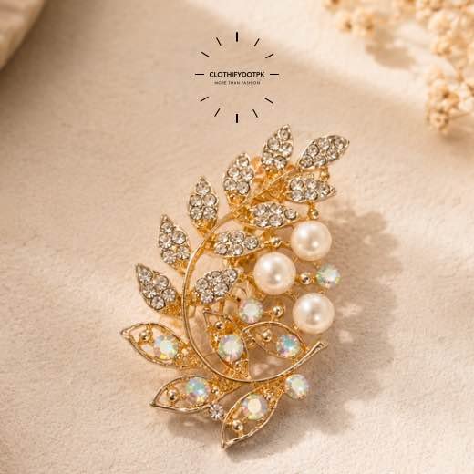 A close-up of a modern, sophisticated brooch featuring a brilliant arrangement of clear rhinestones that catch the light. By Clothifydotpk