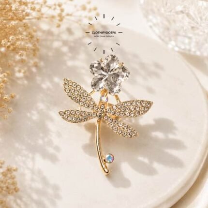A close-up of a modern, sophisticated brooch featuring a brilliant arrangement of clear rhinestones that catch the light. By Clothifydotpk