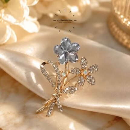 A close-up of a modern, sophisticated brooch featuring a brilliant arrangement of clear rhinestones that catch the light. By Clothifydotpk