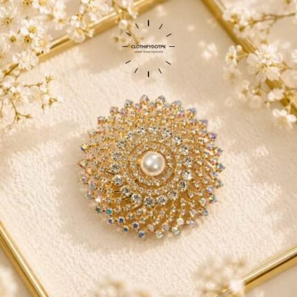 A close-up of a modern, sophisticated brooch featuring a brilliant arrangement of clear rhinestones that catch the light. By Clothifydotpk