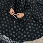 A kid wearing breathable soft swiss lawn modest coverage Namaz Chadar with sleeves, performing salah. By Clothifydotpk