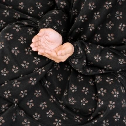 A kid wearing breathable soft swiss lawn modest coverage Namaz Chadar with sleeves, performing salah. By Clothifydotpk