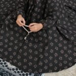 A kid wearing breathable soft swiss lawn modest coverage Namaz Chadar with sleeves, performing salah. By Clothifydotpk