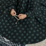 A kid wearing breathable soft swiss lawn modest coverage Namaz Chadar with sleeves, performing salah. By Clothifydotpk
