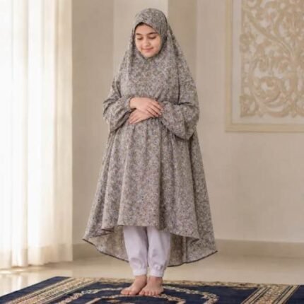 A kid wearing breathable soft swiss lawn modest coverage Namaz Chadar with sleeves, performing salah. By Clothifydotpk