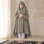 A kid wearing breathable soft swiss lawn modest coverage Namaz Chadar with sleeves, performing salah. By Clothifydotpk