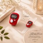 A small, handheld digital tally counter used for tasbeeh, with a simple display showing the current count and a button on top to increment it. BY CLOTHIFYDOTPK