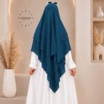 A woman wearing a three layer khimar, with the first layer covering her head and draping down over her chest, and two additional sheer or lightweight layers cascading underneath. BY CLOTHIFYDOTPK