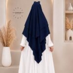 A woman wearing a three layer khimar, with the first layer covering her head and draping down over her chest, and two additional sheer or lightweight layers cascading underneath. BY CLOTHIFYDOTPK