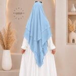 A woman wearing a three layer khimar, with the first layer covering her head and draping down over her chest, and two additional sheer or lightweight layers cascading underneath. BY CLOTHIFYDOTPK