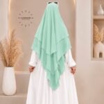 A woman wearing a three layer khimar, with the first layer covering her head and draping down over her chest, and two additional sheer or lightweight layers cascading underneath. BY CLOTHIFYDOTPK