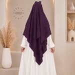 A woman wearing a three layer khimar hijab, with the first layer covering her head and draping down over her chest, and two additional sheer or lightweight layers cascading underneath. BY CLOTHIFYDOTPK