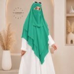 A woman wearing a three layer khimar, with the first layer covering her head and draping down over her chest, and two additional sheer or lightweight layers cascading underneath. BY CLOTHIFYDOTPK