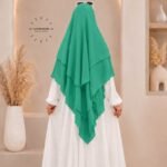 A woman wearing a three layer khimar, with the first layer covering her head and draping down over her chest, and two additional sheer or lightweight layers cascading underneath. BY CLOTHIFYDOTPK