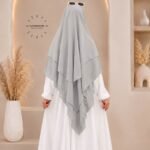 A woman wearing a three layer khimar, with the first layer covering her head and draping down over her chest, and two additional sheer or lightweight layers cascading underneath. BY CLOTHIFYDOTPK