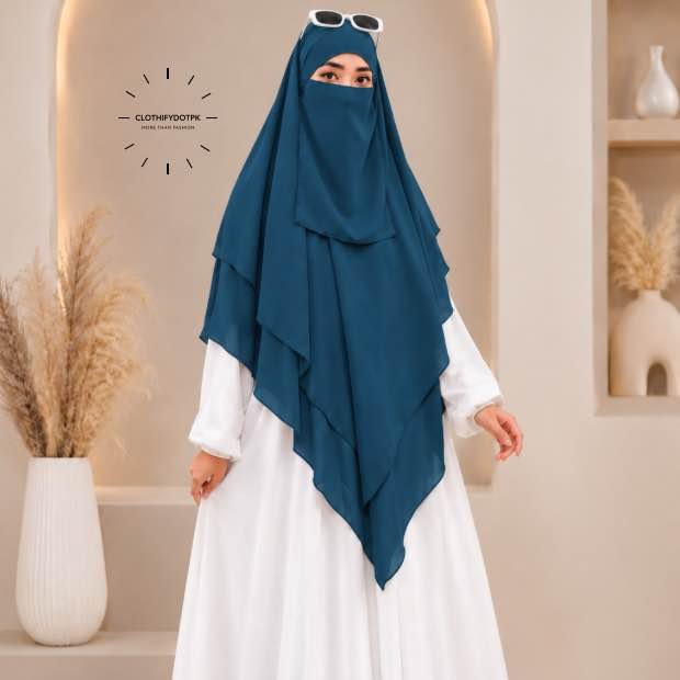 A woman wearing a three layer khimar, with the first layer covering her head and draping down over her chest, and two additional sheer or lightweight layers cascading underneath. BY CLOTHIFYDOTPK
